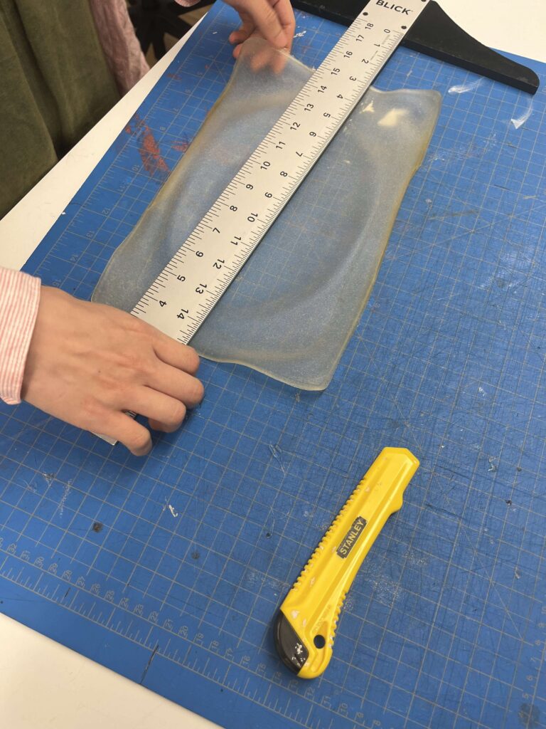 Cutting bioplastic sheet into strips using ruler and X-acto knife.