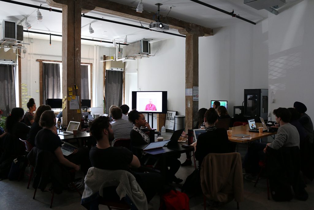 A group of people watching a presentation on a screen.