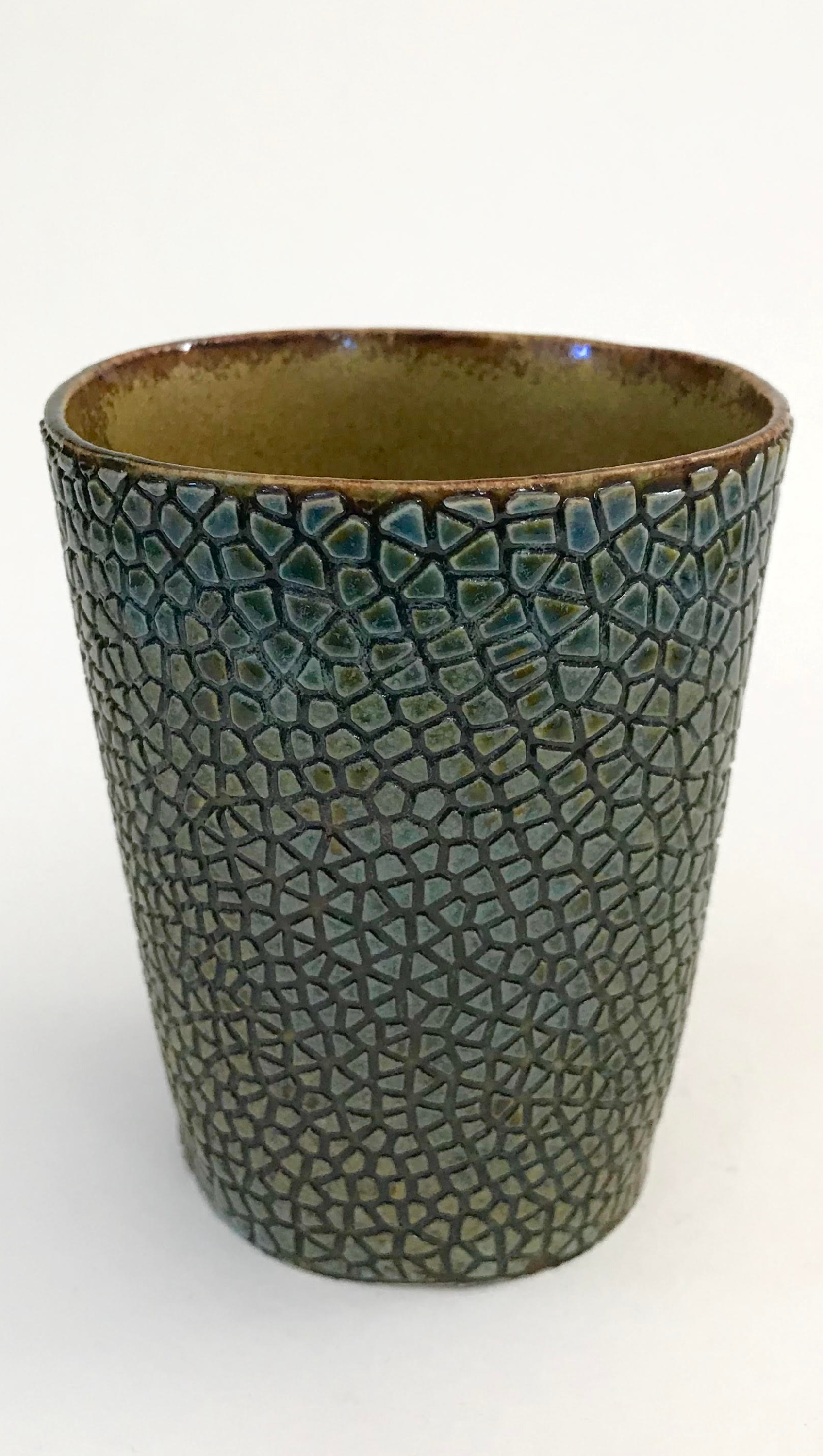 a clay cup with a fragmented skin made of intersecting lines