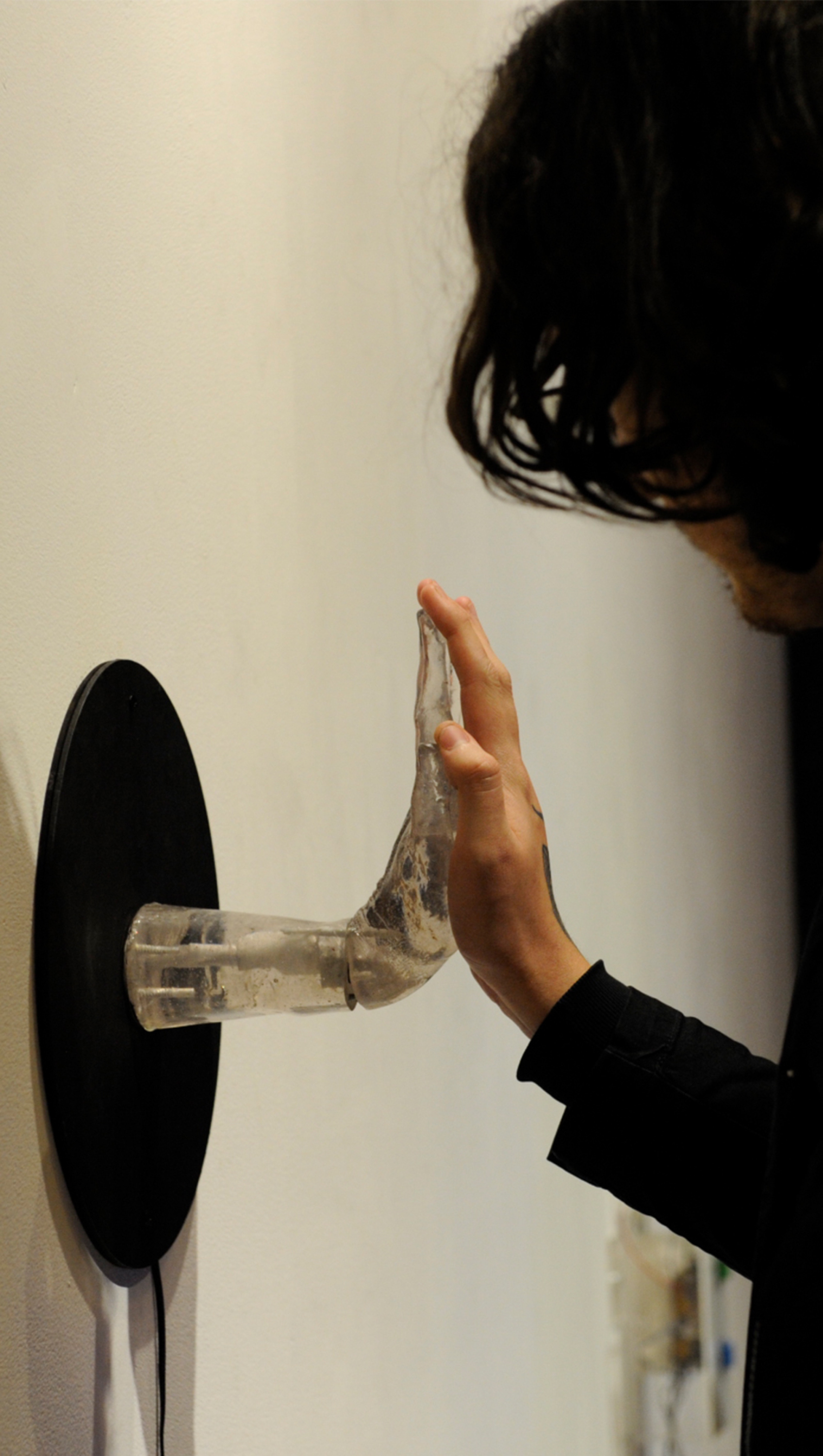 Photo of 'Sensitive Technological' (2018) showing the transparent hand-shaped piece on the left, and a human hand interacting with it on the right. (Photo: Rodrigo Bello Marroni)