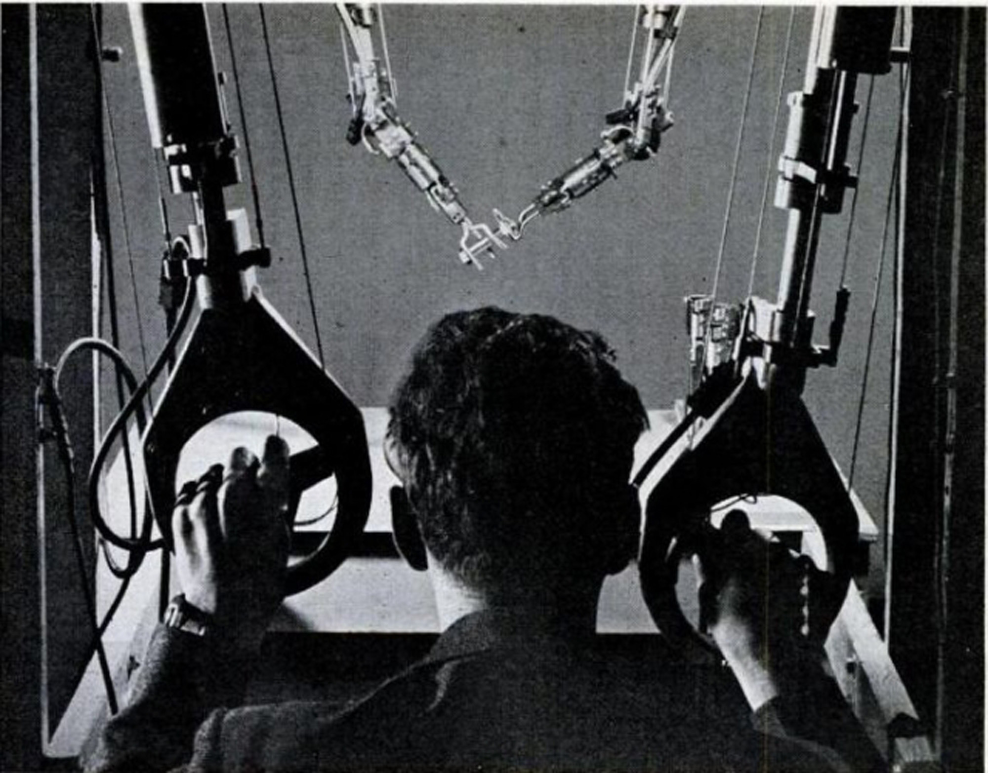 An operator using the GE Master-Slave Manipulator, which appears as two robotic puppet controls