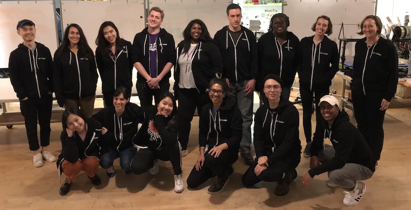 A group photo of 14 counselors wearing black ITP Camp hoodies with white text.