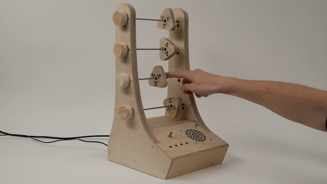 A video demonstrating "Abacusynth", an abacus-shaped synthesizer by Elias Jarzombek. A hand is moving and spinning triangle-shaped objects along a metal bar, similar to beads on an abacus, to control the synthesizer.