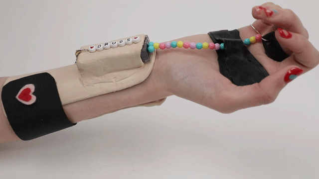 A video demonstrating "Pill Popper", a wearable pill dispenser strapped to someone's wrist, opening and closing. Project by Zoe Cohen.