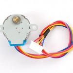 Photo of a stepper motor. This motor is approximately 2 inches (5cm) on diameter, with an off-center shaft at the top, and wires protruding from the bottom. You can tell a stepper motor from a DC motor because steppers have at least four wires, while regular DC motors have two. 