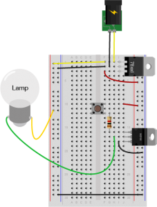 Breadboard drawing of a transistor controlling an incandescent lamp with a pushbutton. The drawing is similar to the breadboard drawing with the pushbutton above, but the motor has been replaced with an incandescent lamp and the diode has been removed.