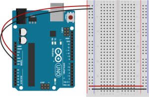 An Arduino Uno on the left connected to a solderless breadboard, right. The Uno's 5V output hole is connected to the red column of holes on the far left side of the breadboard. The Uno's ground hole is connected to the blue column on the left of the board. The red and blue columns on the left of the breadboard are connected to the red and blue columns on the right side of the breadboard with red and black wires, respectively. These columns on the side of a breadboard are commonly called the buses. The red line is the voltage bus, and the black or blue line is the ground bus. 