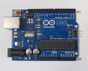 An Arduino Uno. The USB connector is facing to the left, so that the digital pins are on the top of the image, and the analog pins are on the bottom.