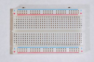 A short solderless breadboard with two rows of holes along each side. There are no components mounted on the board. The board is oriented sideways so that the long rows of holes are on the top and bottom of the image.