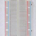 A short solderless breadboard with two rows of holes along each side. There are no components mounted on the board.
