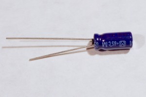 Electrolytic capacitor. This component has a tubular top and two wire legs coming out of one end of the tube. They are generally polarized. The longer leg is the positive leg. You measure the capacitance between the two legs. Electrolytic capacitors are generally higher capacitance than ceramic capacitors.