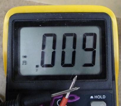 Photo detail of .a meter measuring continuity. The two probes are touching each other. The meter reads .009. There is a diode symbol and a musical note on the left side of the screen. 