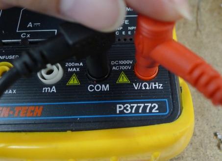 Photo detail of the bottom of a multimeter, showing the red lead not plugged in all the way. 