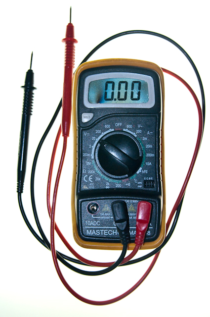Multimeter tool. This tool has a dial to set the function, and three holes into which to plug the testing leads. The leads are currently plugged into the center hole and the right hand hole.