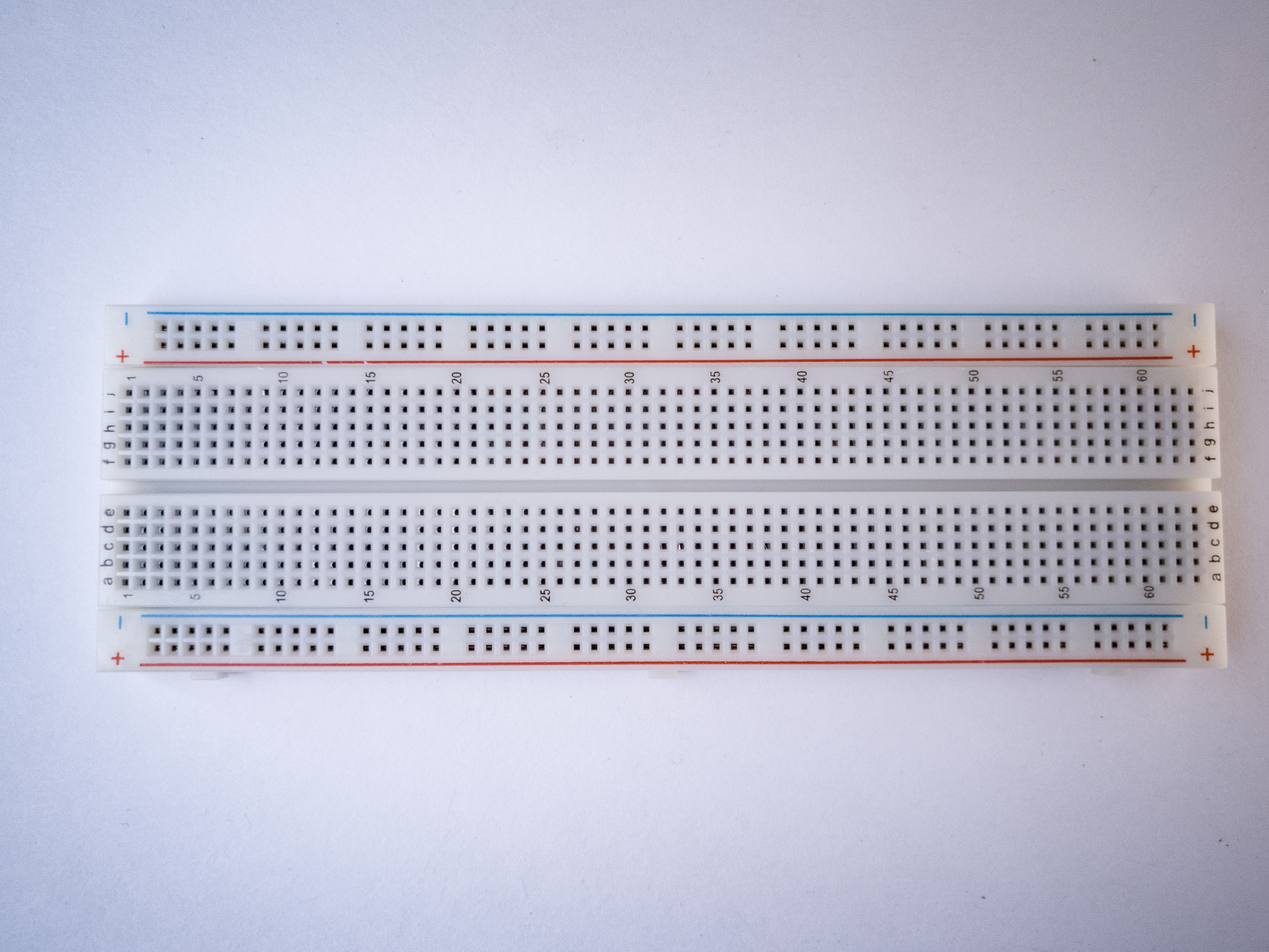 Photo of a solderless breadboard. The . board is turned sideways so that the side rows are on top and bottom in this view. There are no components mounted on the board.