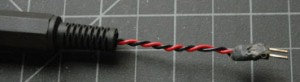 Photo of an assembled DC power connector. Red and black wires, twisted together, protrude from the connector. They terminate in a pair of header pins, The connection between the wires and the header pins, previously soldered, is hot glued for insulation. 