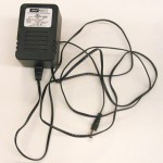 Photo of a DC power supply. A rectangular block approximately 2 inches by 3 inches with plugs to plug into the wall. A wire extends from the plug to connect with your circuit.