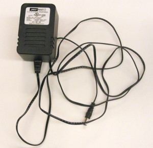 Photo of a DC power supply. A rectangular block approximately 2 inches by 3 inches with plugs to plug into the wall. A wire extends from the plug to connect with your circuit.