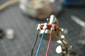 Photo of a potentiometer with ring contacts. Three wires are soldered to the three contacts, from left to right: black wire, blue wire, red wire.