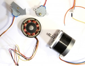 Photo of three stepper motors. The center one is opened up to show the coils inside.