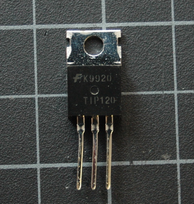 TIP120 Transistor. The body of the component is black, and it has a silver tab on top with a hole. It has three legs. When you're holding the component facing you (with the bulging part forward), the legs are, from left to right: base, collector, emitter.