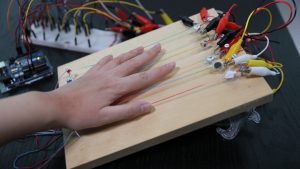a hand placed on strings to feel music through vibration