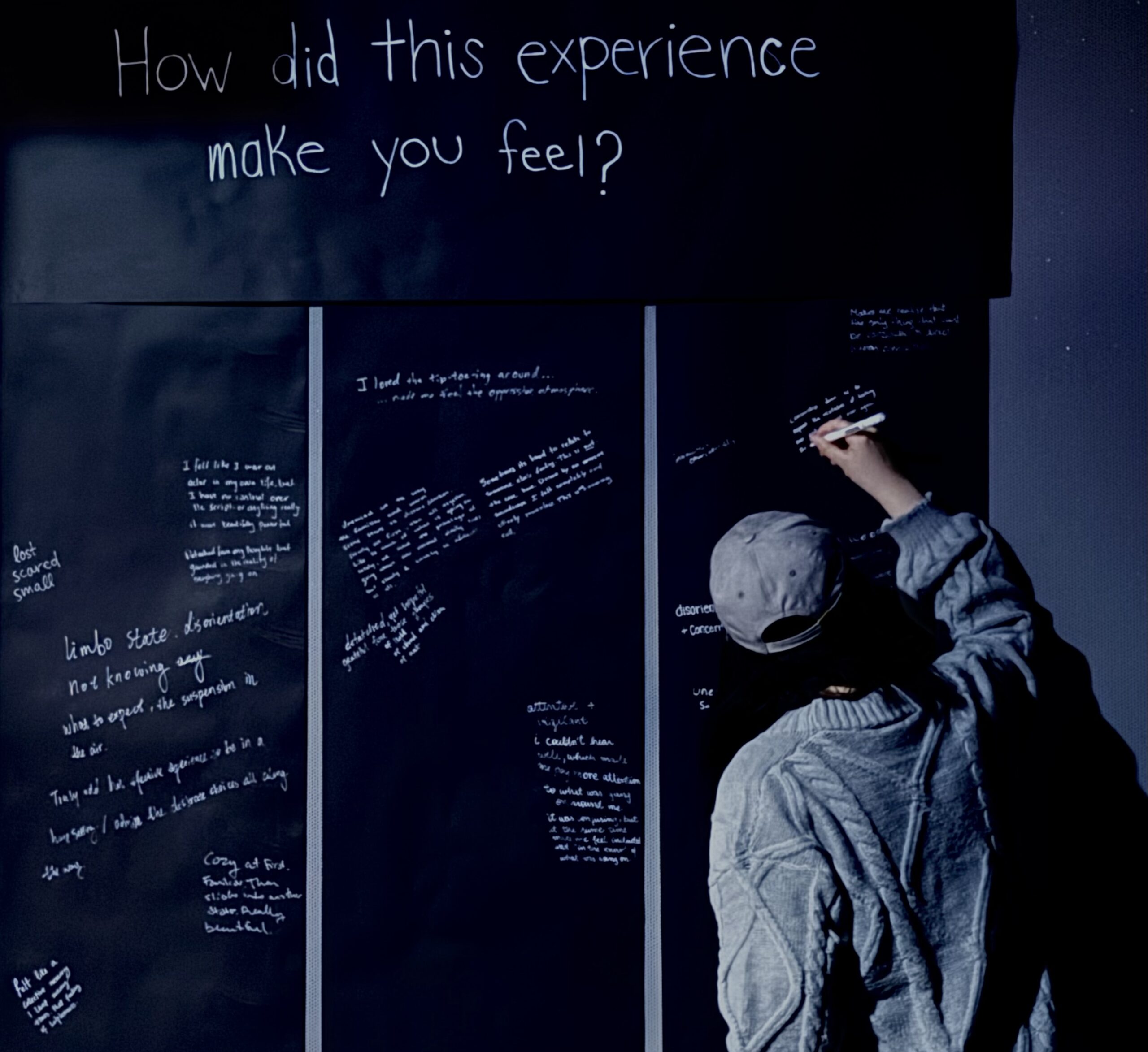 A person answering the question "how did the experience make you feel"? on a black sheet presented before them.