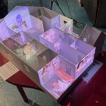 model of a house, made of white-painted wood, with images projected on top.