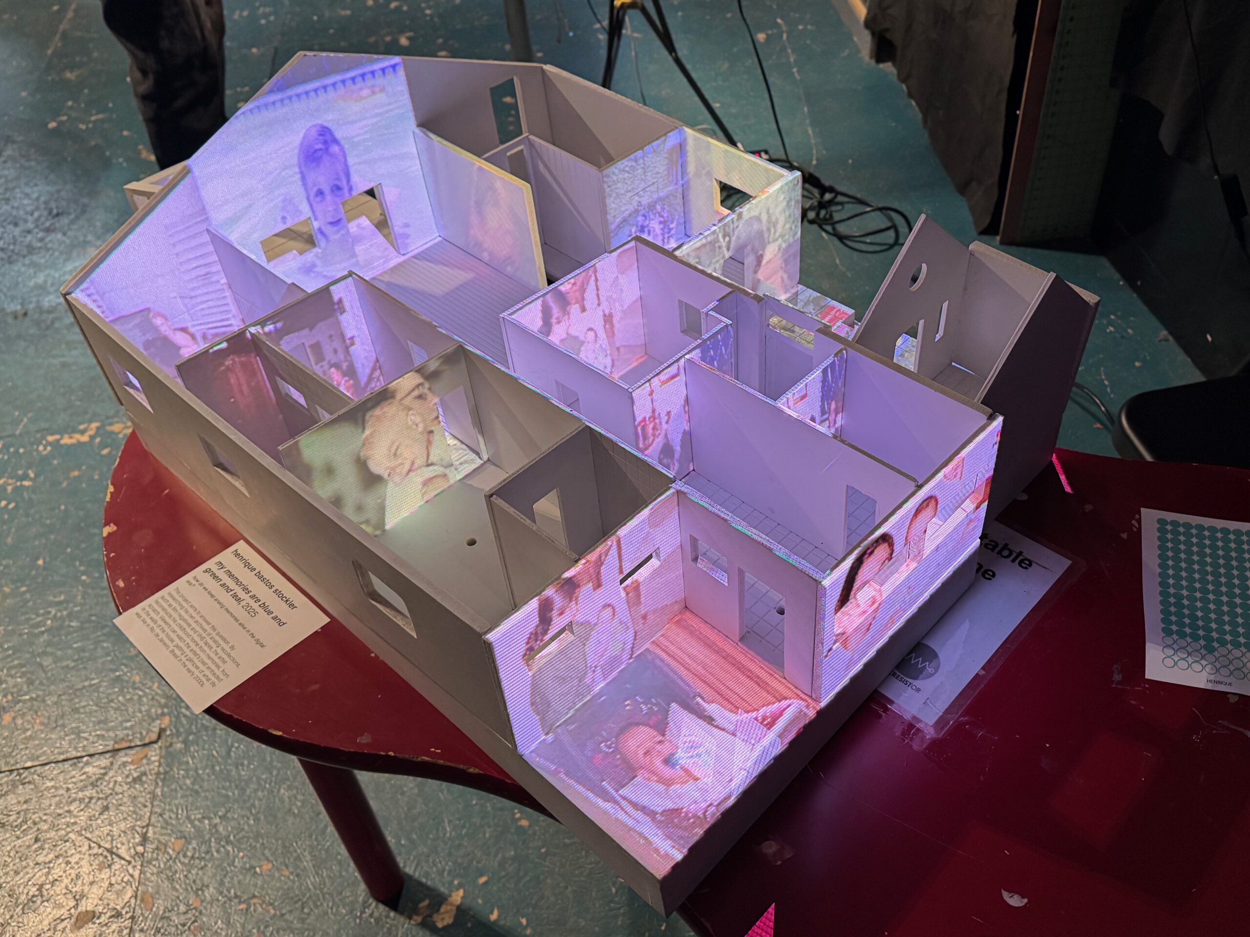 model of a house, made of white-painted wood, with images projected on top.