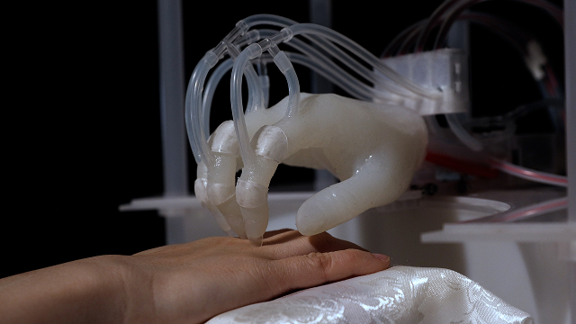 a close up of a soft robotic hand scratching a human hand