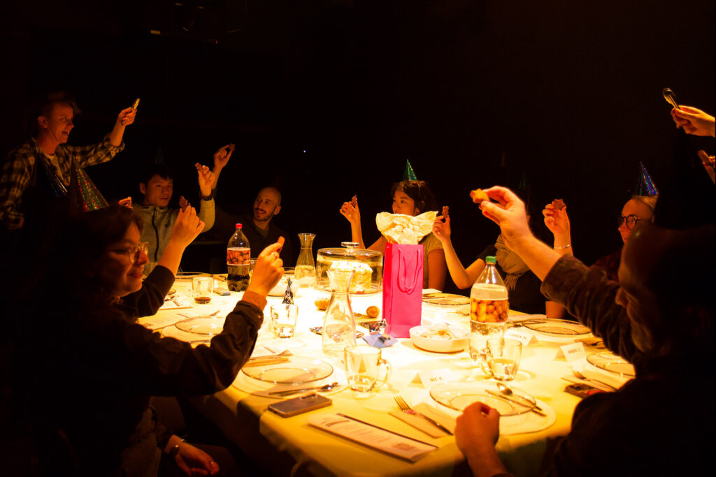 A table of guests cheers while holding potato nuggets.
