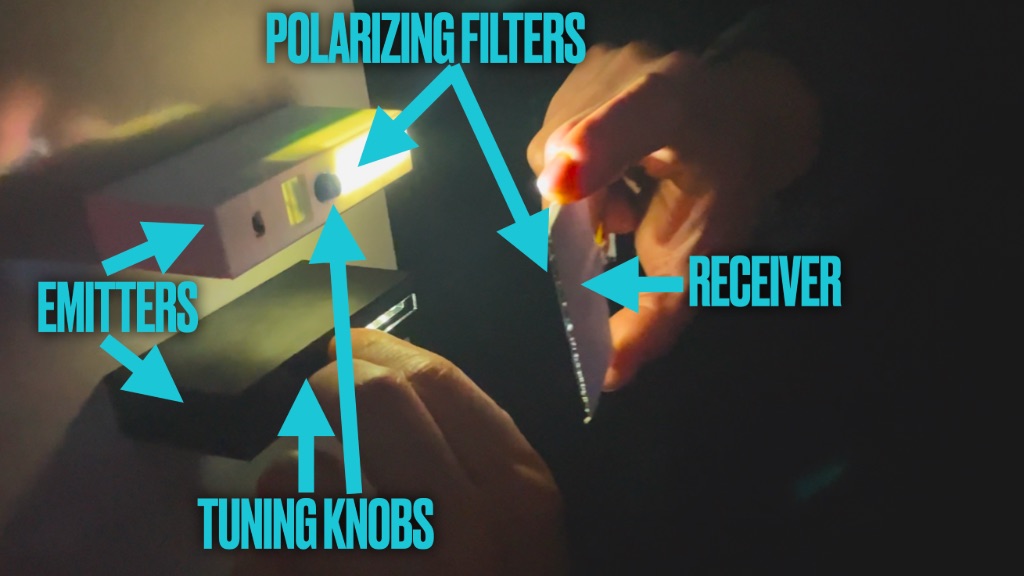 Two small devices that emit light that is received with a hand-held solar panel.