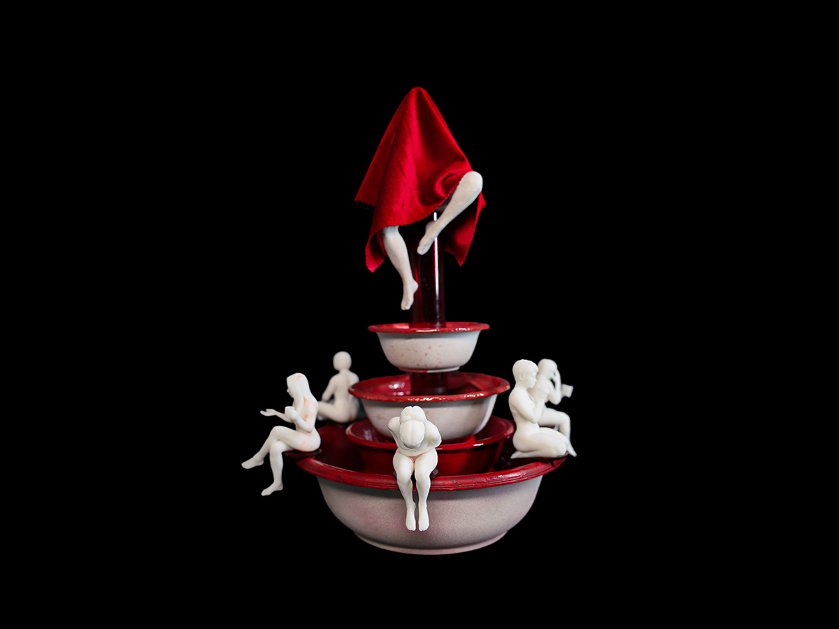 A red and white fountain with white 3d printed resin figures.