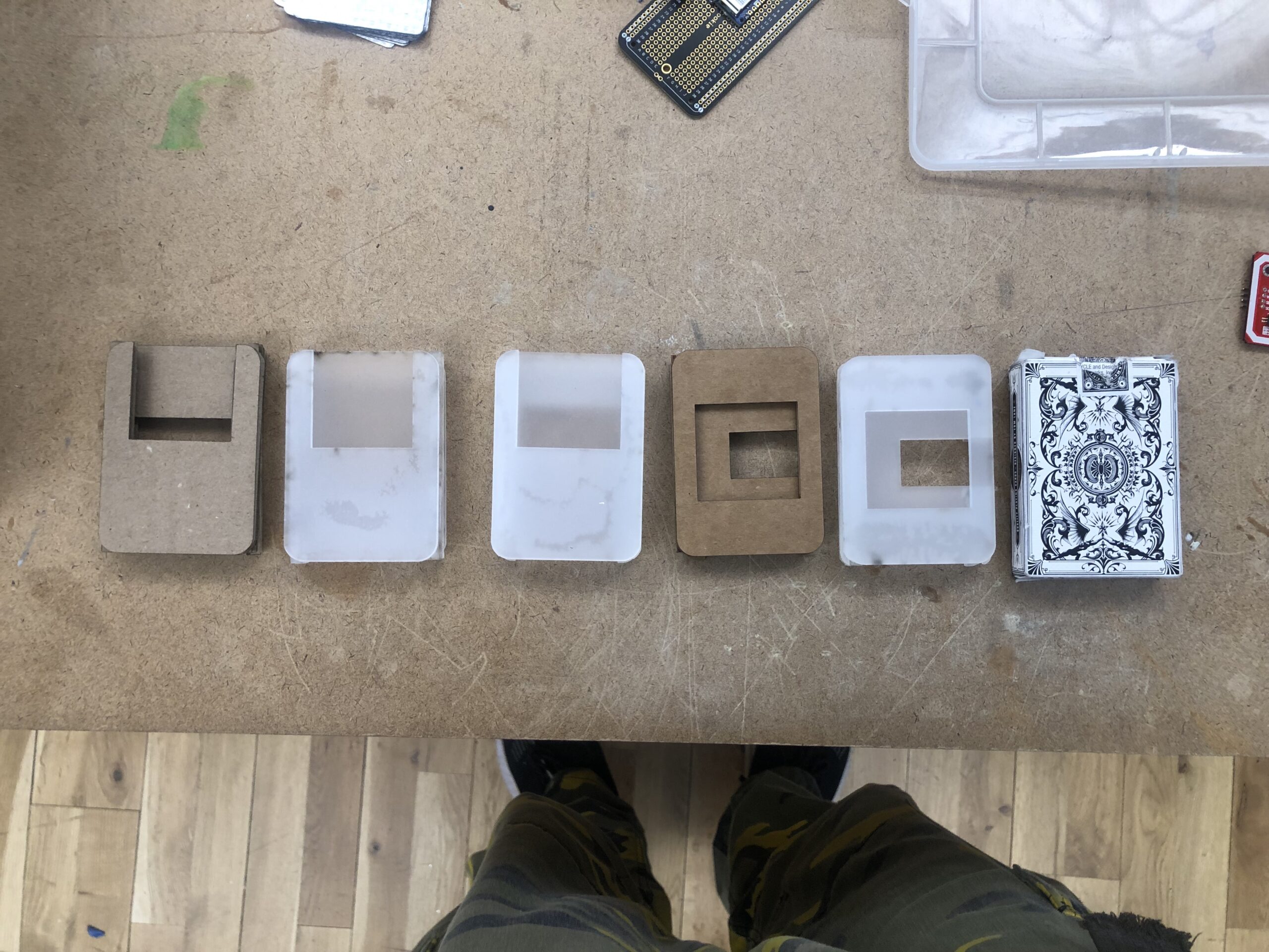 Six different version of the original body lined up side to side. 1 and 4 are cardboard drafts. 2,3, and 5 are acrylic drafts and 6 is just the box itself