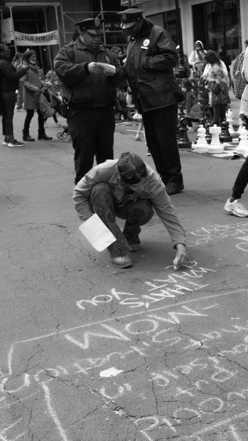 Young woman writing down a quote on the sidewalk using chalk.
