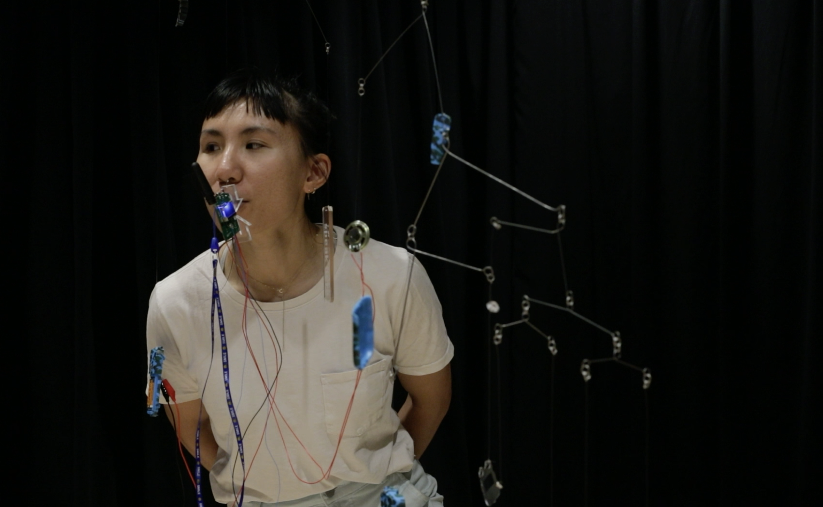 a person speaks into the microphone of a walkie talkie in one of two kinetic mobiles titled 'walkie & talkie'