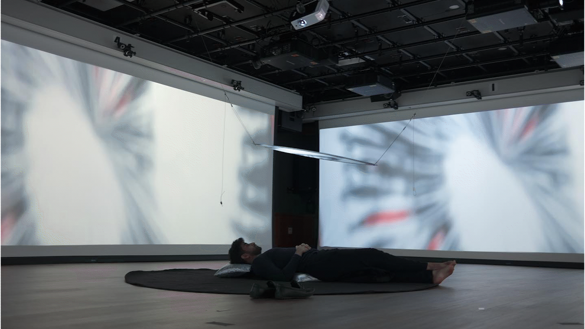 The four-sided projected space is abstractly depicted by posters, floating three wireframe human bodies
