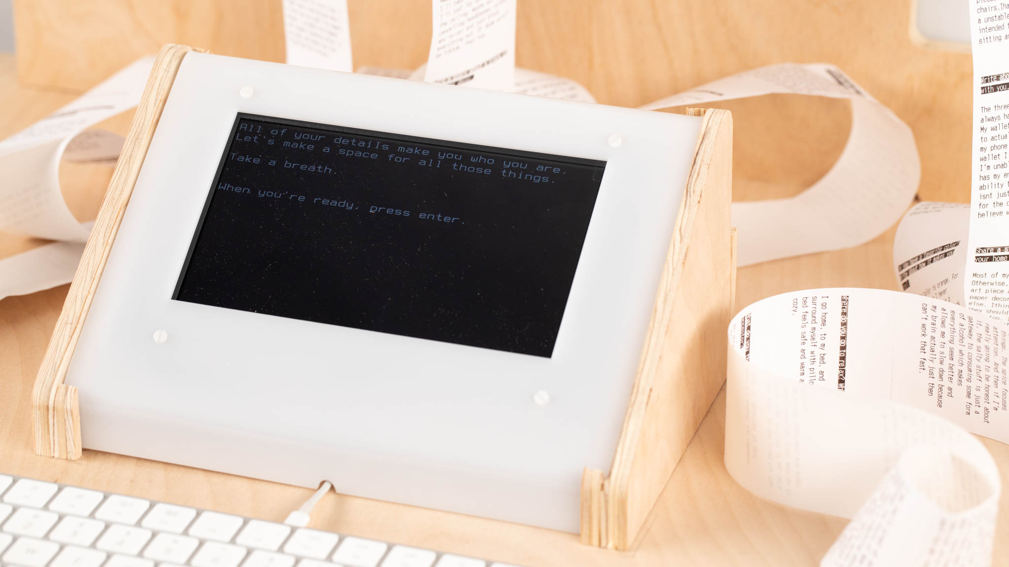 Console screen mounted to white acrylic, surrounded by rolls of paper. The screen reads the text included in caption.