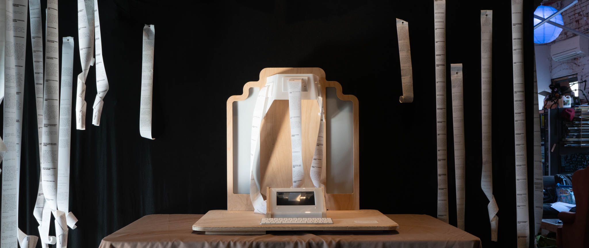 Altar on a table, surrounded by printed paper receipts hanging from a black backdrop.